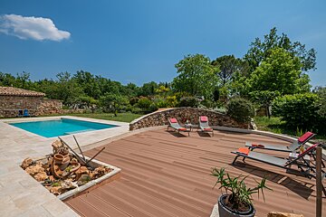A wooden deck with lawn chairs and a pool in the background