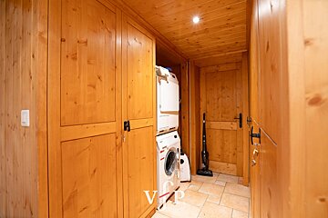 A washer and dryer are stacked on top of each other in a wooden room