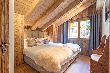 A bedroom with a wooden ceiling and a bed