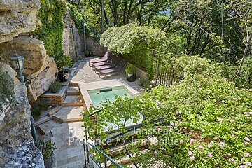 A swimming pool is surrounded by trees and a sign that says provence immobilier