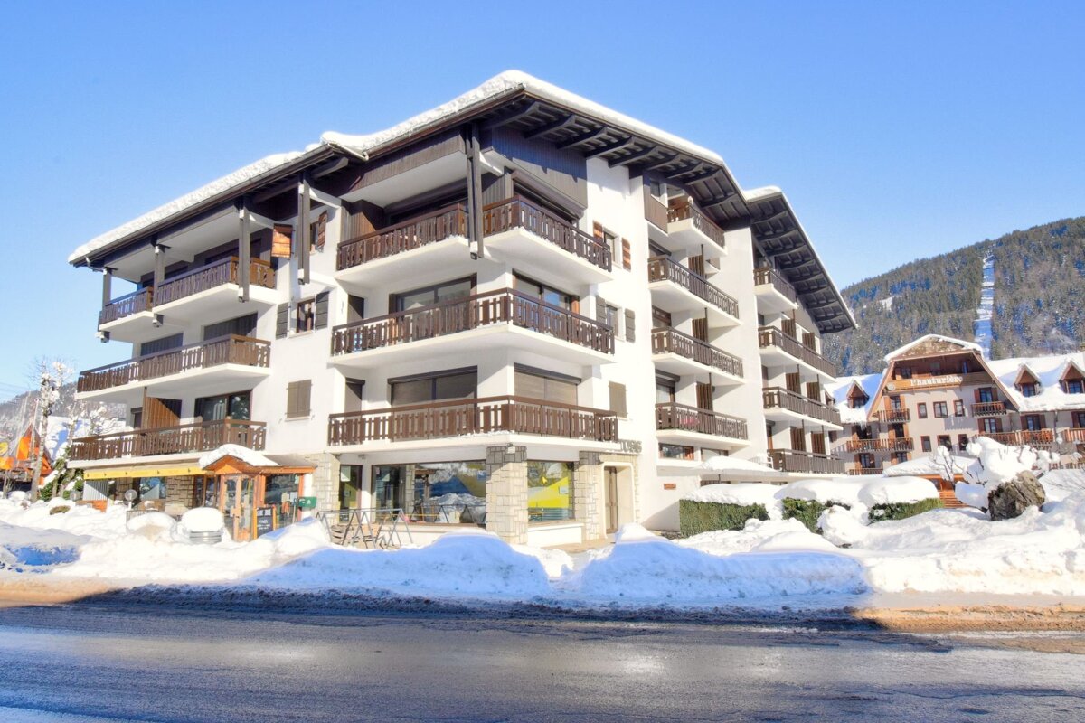 A snowy, multi-story alpine chalet building under a clear blue sky in winter.