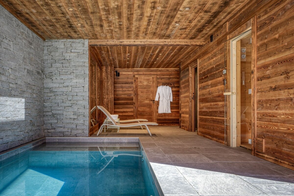 A wooden room with a swimming pool and chairs