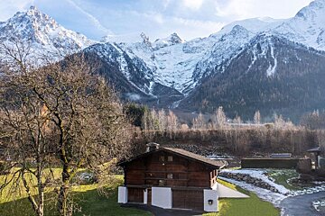 A snowy mountain is behind a small house