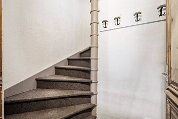 A spiral staircase with hooks on the wall with the letter t on them