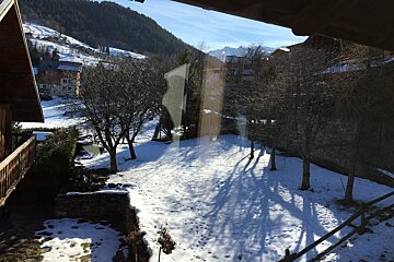 A snowy yard with trees and mountains in the background