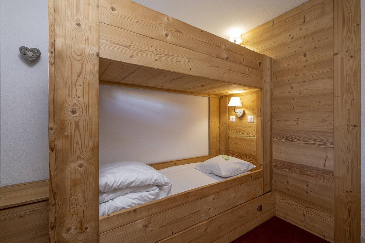A wooden bunk bed with a white comforter on it