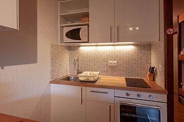 A small kitchen with a sink stove and microwave