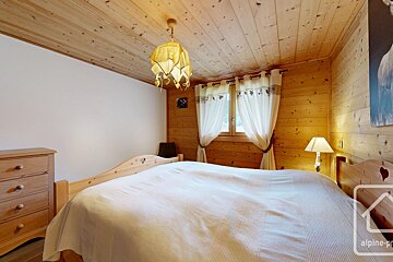 A bedroom with a bed and a lamp and the word alpine on the corner