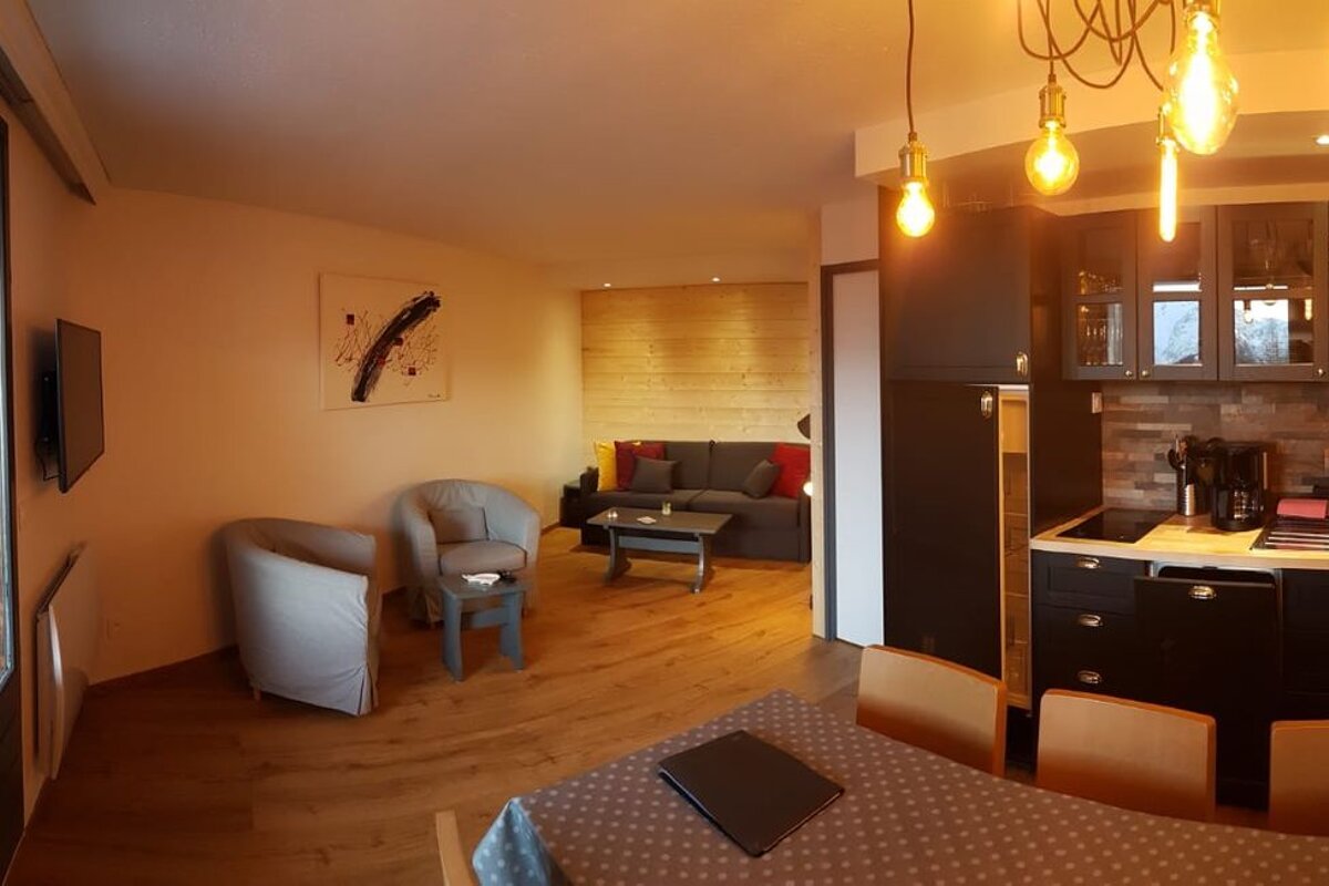 A living room with a couch and chairs and a kitchen