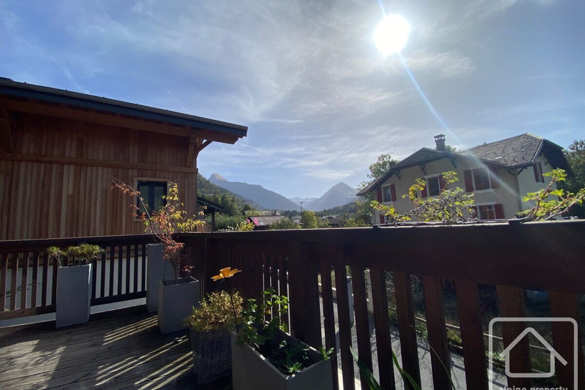 A balcony with potted plants and a house in the background