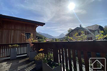 A balcony with potted plants and a house in the background