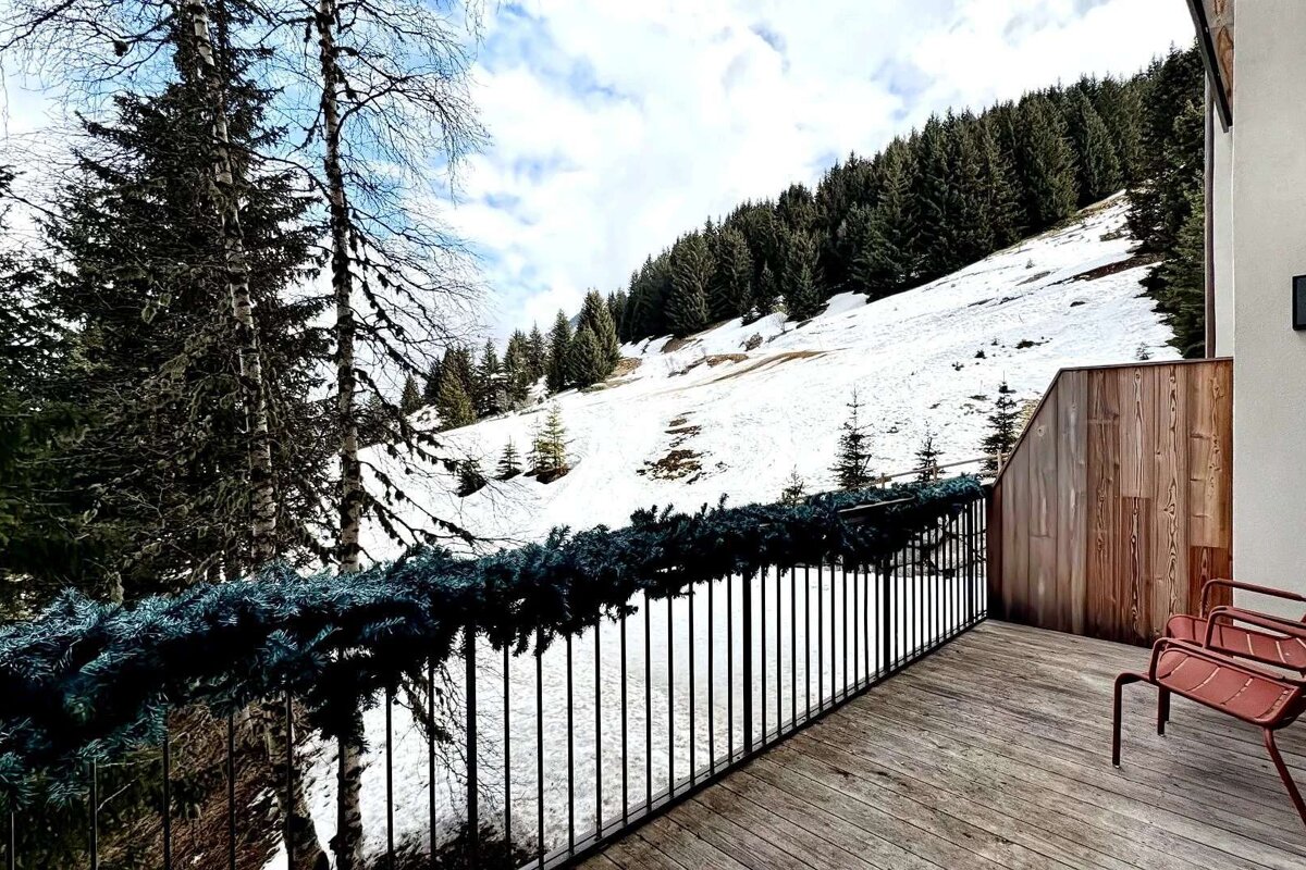 A balcony overlooking a snowy mountain with trees in the background