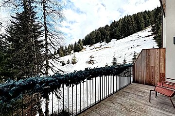 A balcony overlooking a snowy mountain with trees in the background