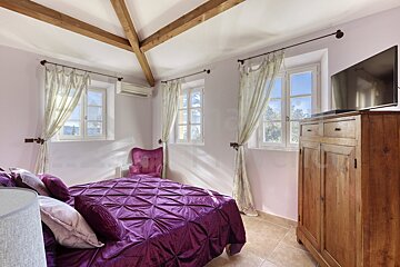 A bedroom with a purple bed and a television