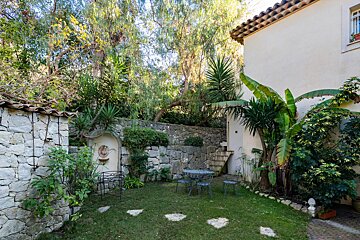 A garden with a stone wall and a table and chairs