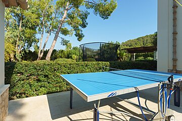 A blue ping pong table with a trampoline in the background