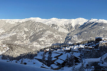 A snowy mountain range with a white management logo in the foreground