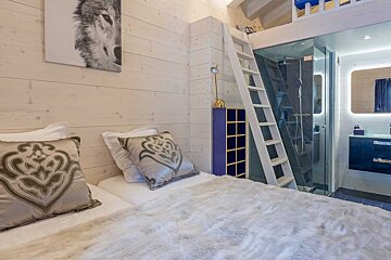 A bedroom with a bed a chair and a mirror