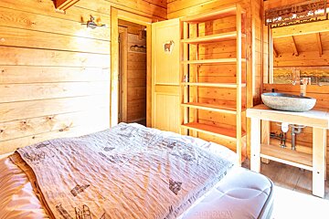 A wooden room with a bed and a sink with the word design on it