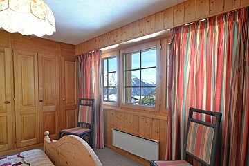 A bedroom with a bed and chairs and striped curtains