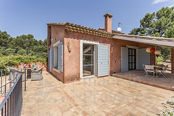 A patio with a table and chairs in front of a house that is for sale