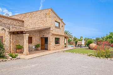 A stone house with a patio and a satellite dish on the roof