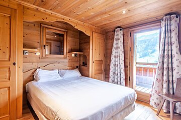 A wooden bedroom with a bed and a window