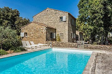 A stone house with a swimming pool in front of it