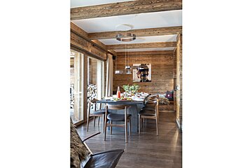 A dining room with a table and chairs and a painting on the wall