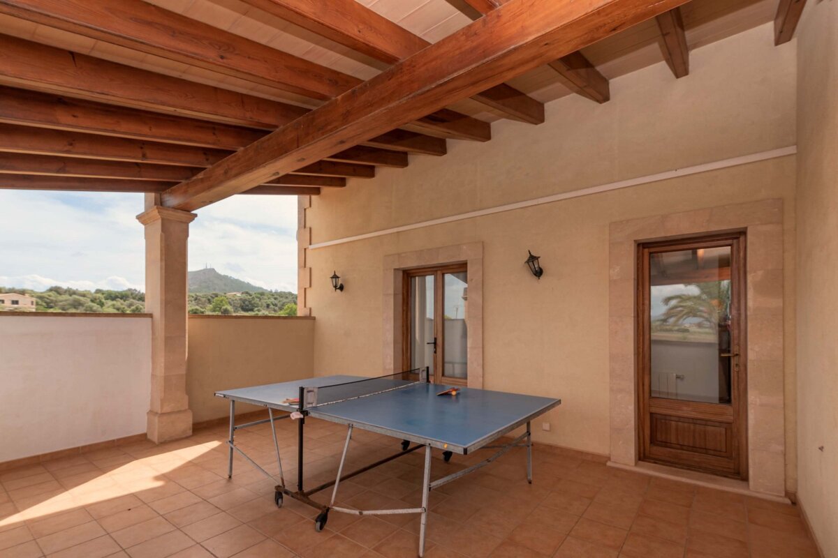 A ping pong table on a balcony with a mountain in the background