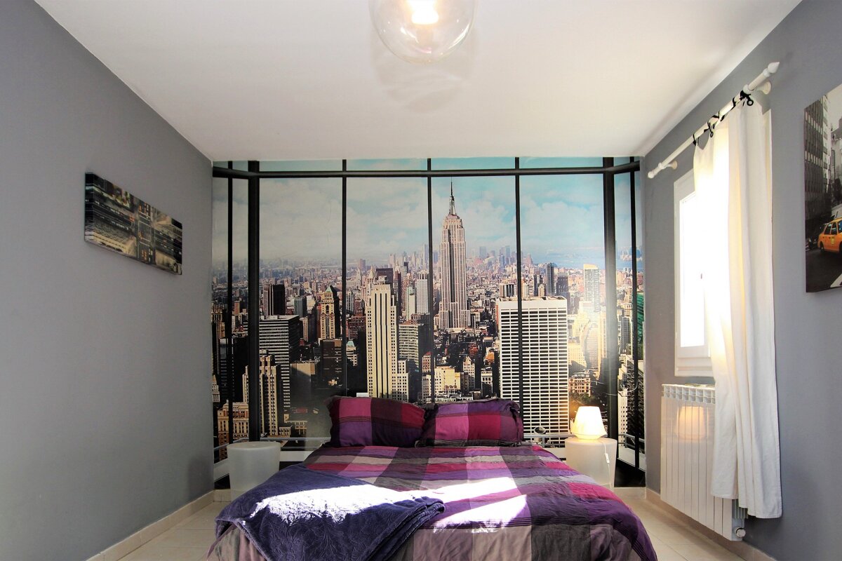 A bedroom with a picture of new york city on the wall