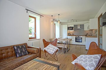 A living room with a couch and chairs and a kitchen