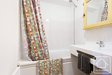 A bathroom with a colorful shower curtain and a sign that says alpine property
