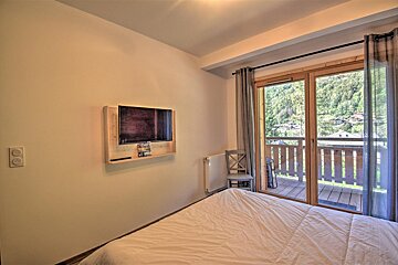 A bedroom with a bed and a television on the wall