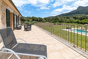 A balcony overlooking a swimming pool with a mountain in the background