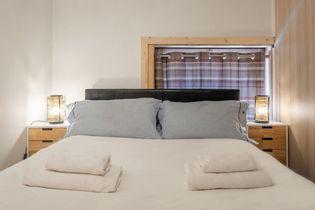 A bedroom with a bed and two lamps on the nightstands