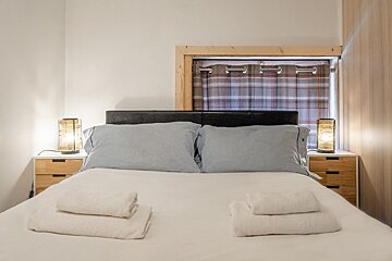 A bedroom with a bed and two lamps on the nightstands