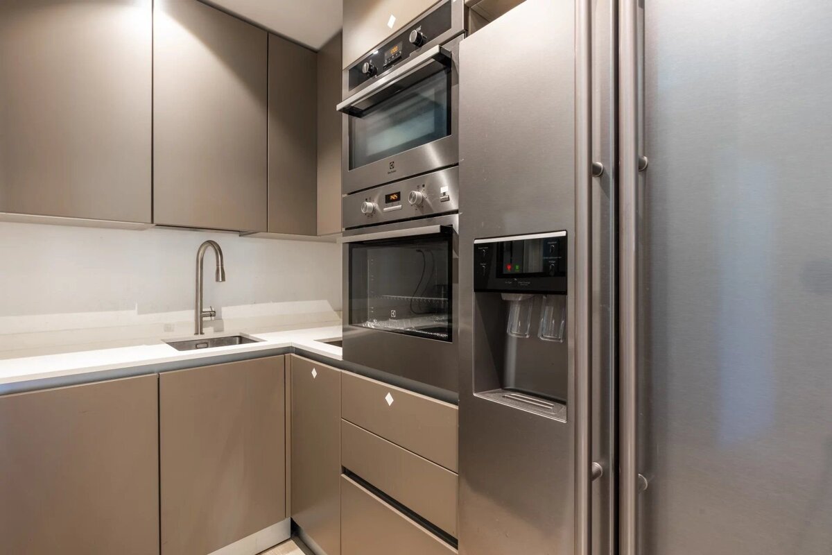 A modern kitchen featuring sleek taupe cabinetry, built-in double ovens, and a stainless steel refrigerator.