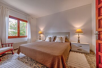 A bedroom with a large bed and two lamps
