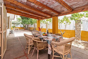 A patio with a table and chairs under a wooden roof
