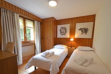 A bedroom with two twin beds and two paintings of bears on the wall