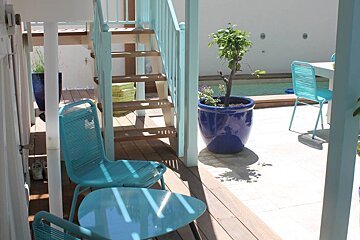 A blue potted plant sits on a deck next to a table and chairs