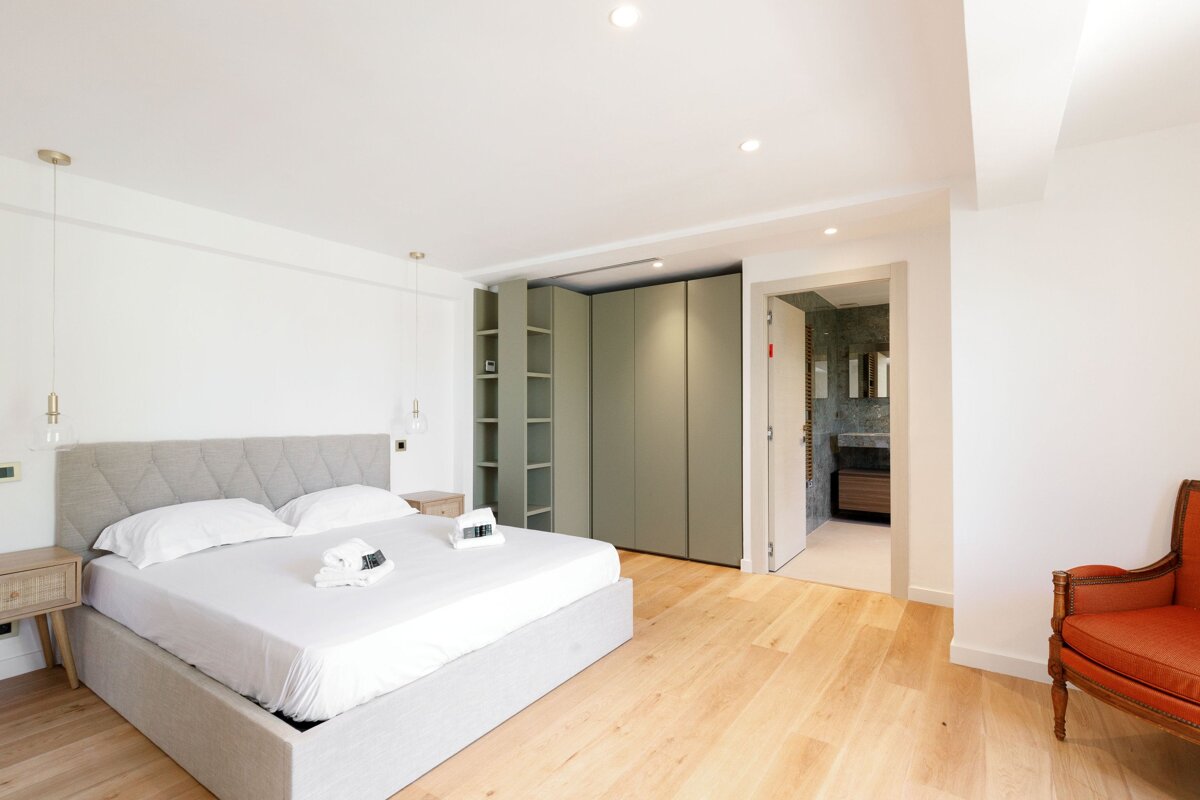 A bedroom with a large bed and a chair