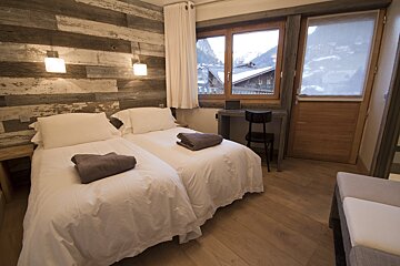 A bedroom with two beds and a window with mountains in the background