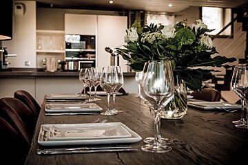A table set with plates and glasses and a vase of flowers