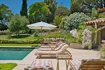 A row of lounge chairs are lined up next to a swimming pool