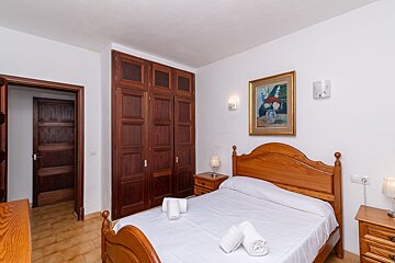 A bedroom with a painting on the wall above the bed