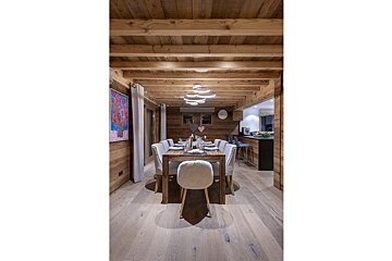 A dining room with a table and chairs and a painting on the wall