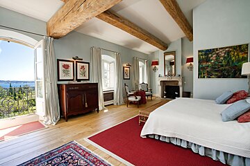 A bedroom with a large bed and a fireplace
