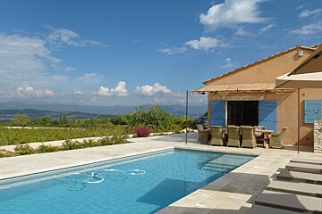 A house with blue shutters sits next to a swimming pool